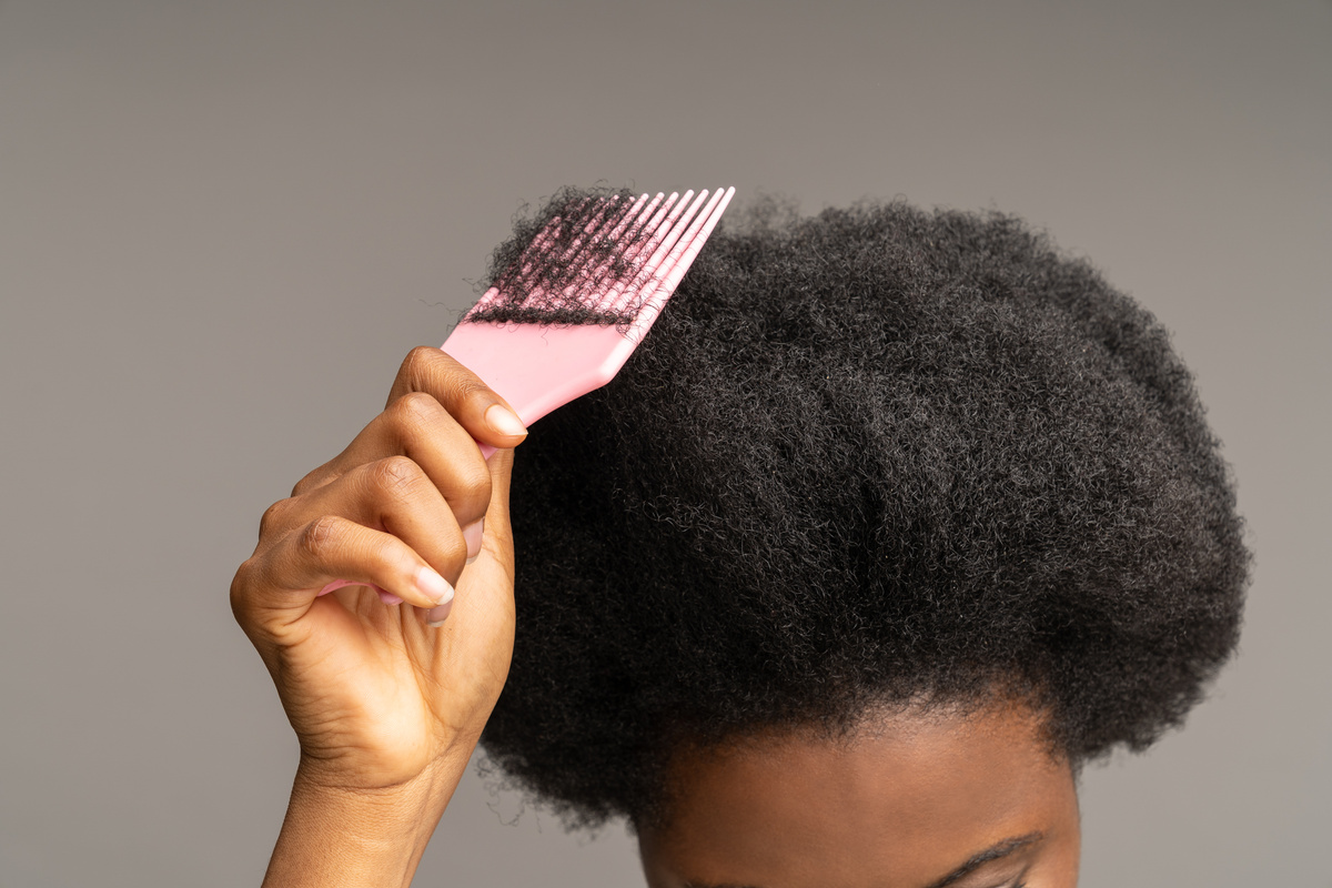  Ethnic Female Hand Holds Hairbrush at Wavy Afro Hairdo